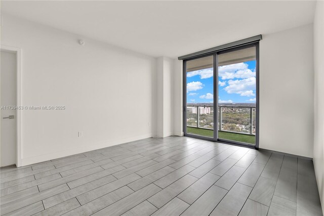 empty room featuring a wall of windows and light hardwood / wood-style floors