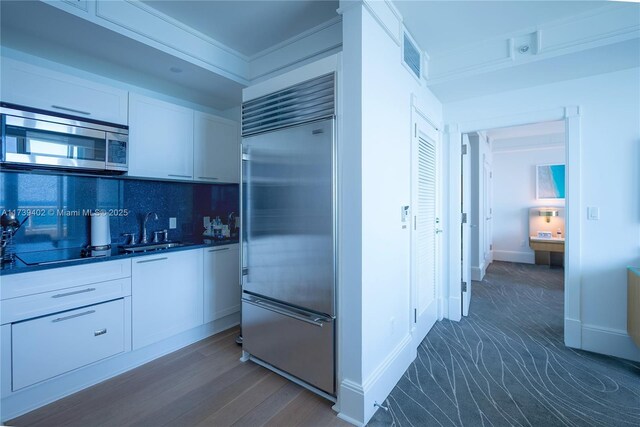 kitchen featuring sink, dark hardwood / wood-style flooring, stainless steel appliances, decorative backsplash, and white cabinets