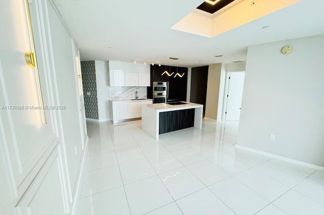 kitchen with light tile patterned floors, white cabinetry, a center island, tasteful backsplash, and stainless steel double oven