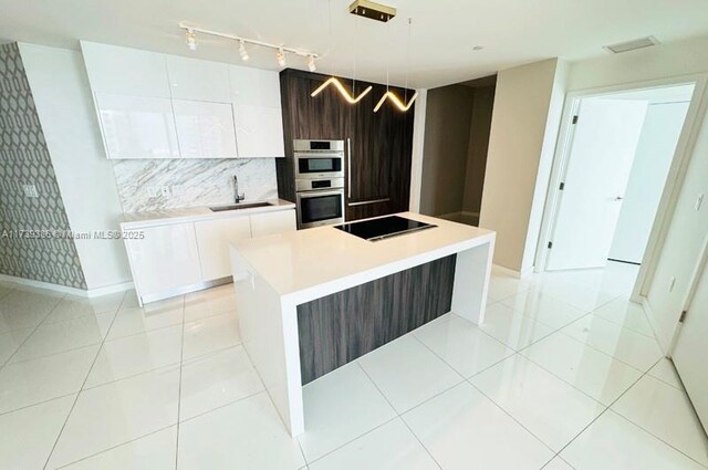 kitchen featuring a kitchen island, pendant lighting, sink, white cabinets, and black electric stovetop