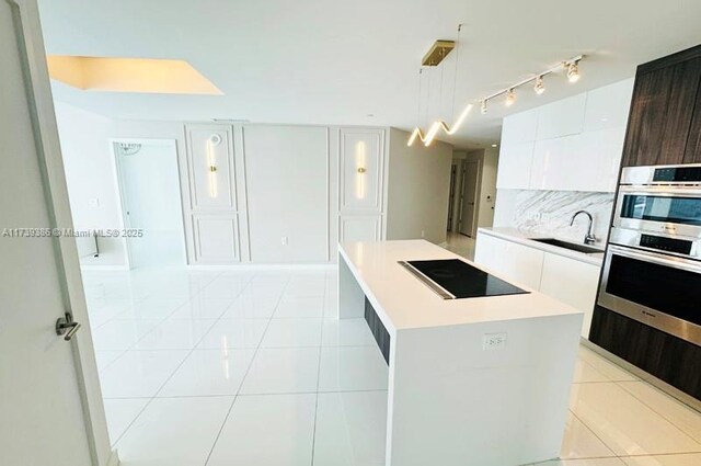 kitchen featuring dark brown cabinetry, sink, a kitchen island, black electric stovetop, and white cabinets