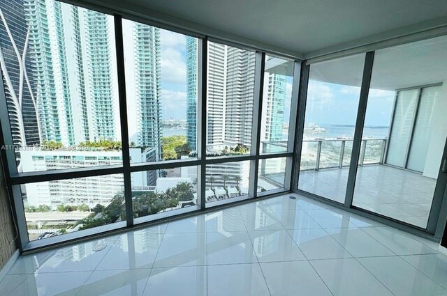 unfurnished room with expansive windows, a healthy amount of sunlight, and tile patterned flooring