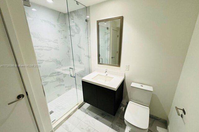 bathroom featuring vanity, a shower with shower door, and toilet