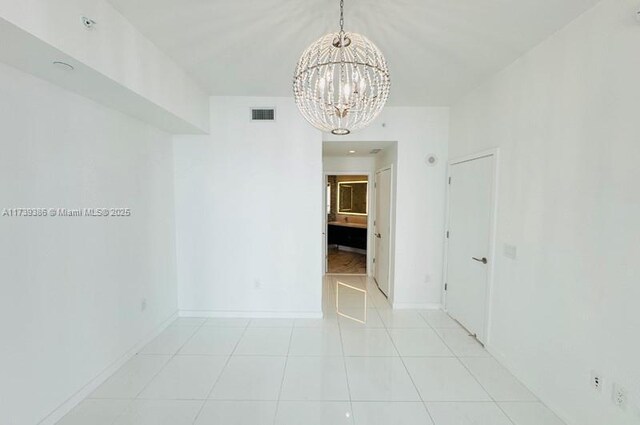 unfurnished room featuring light tile patterned flooring and an inviting chandelier