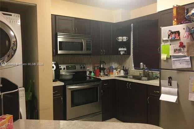 kitchen with stainless steel appliances, tasteful backsplash, stacked washer and dryer, and sink