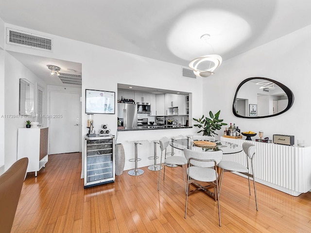 dining area with beverage cooler and light hardwood / wood-style flooring