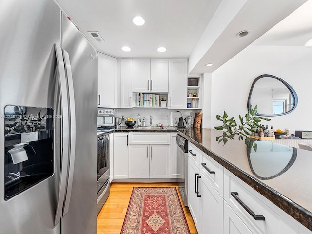 kitchen with appliances with stainless steel finishes, sink, light hardwood / wood-style flooring, and white cabinets