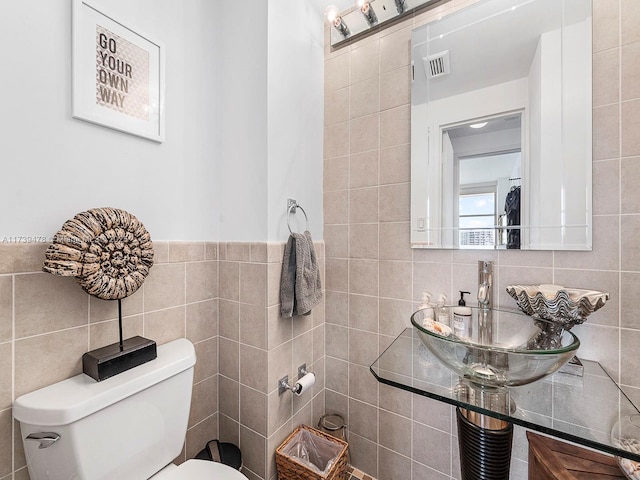 bathroom featuring toilet, sink, and tile walls