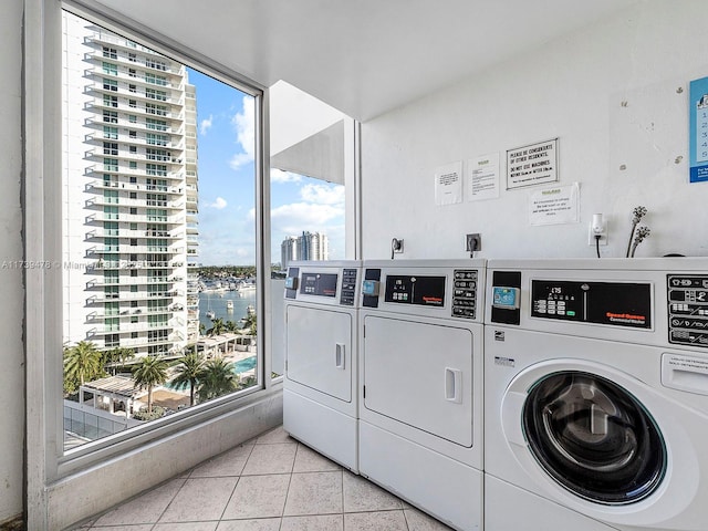 clothes washing area with separate washer and dryer, light tile patterned floors, and a healthy amount of sunlight