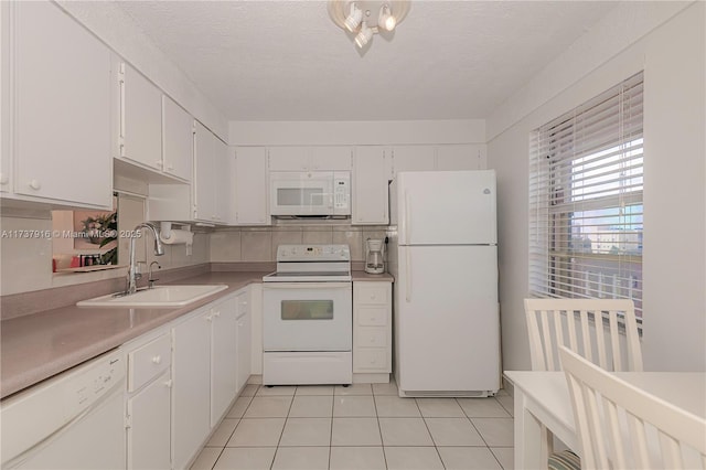 kitchen with white appliances, light countertops, a sink, and white cabinets