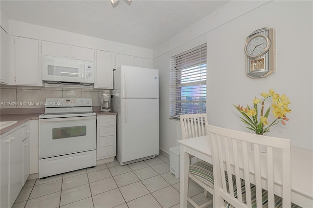 kitchen with white appliances, light tile patterned floors, white cabinets, light countertops, and backsplash