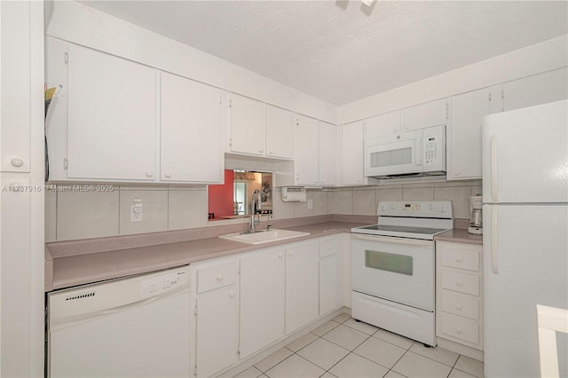 kitchen with white appliances, white cabinetry, light countertops, and a sink