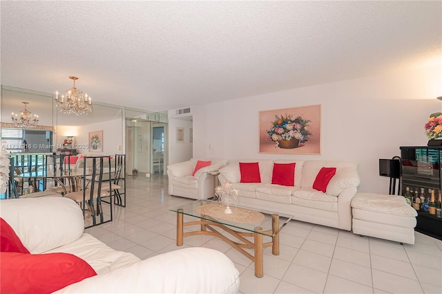 living room featuring a textured ceiling, tile patterned flooring, visible vents, and a notable chandelier