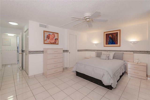 bedroom featuring ceiling fan, light tile patterned floors, a textured ceiling, and a closet