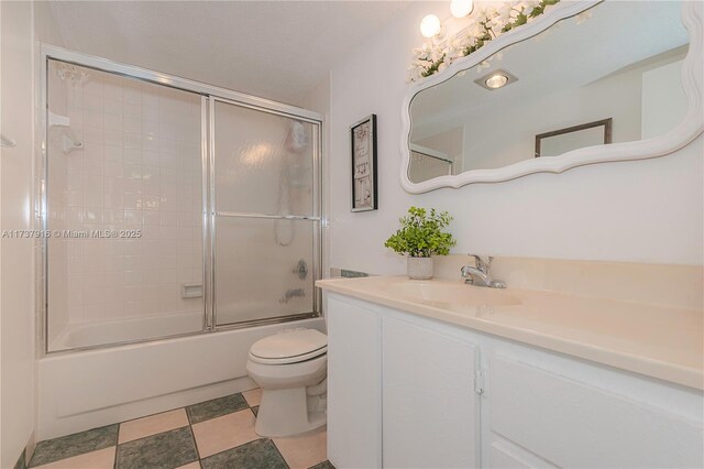 full bathroom featuring vanity, bath / shower combo with glass door, and toilet