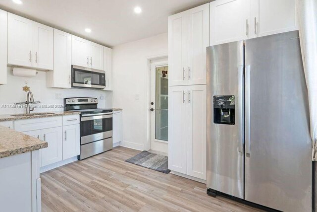 kitchen with light stone counters, sink, white cabinets, and appliances with stainless steel finishes