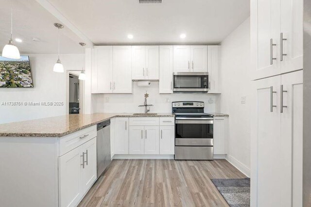 kitchen featuring stainless steel appliances, light stone countertops, sink, and white cabinets