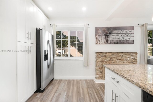 kitchen featuring white cabinetry, plenty of natural light, light stone counters, and stainless steel fridge with ice dispenser