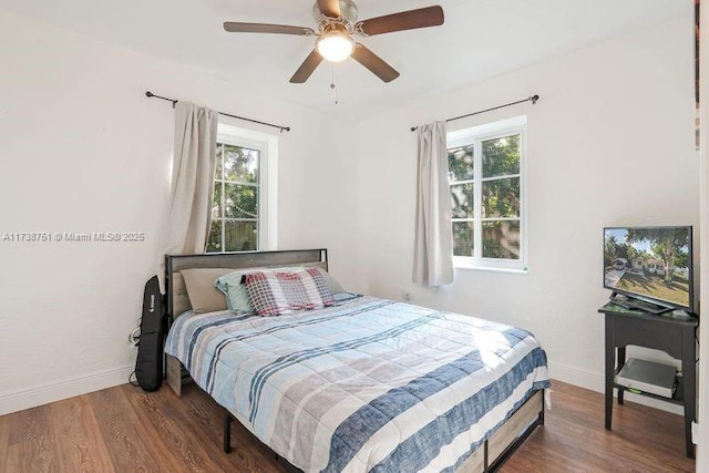 bedroom with ceiling fan, dark hardwood / wood-style floors, and multiple windows