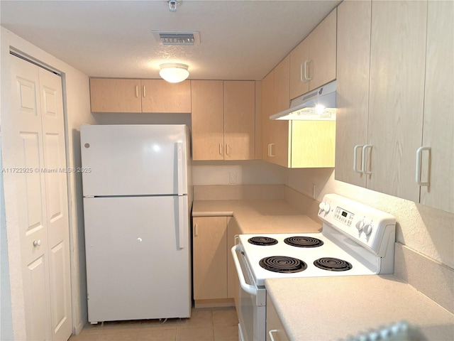 kitchen featuring under cabinet range hood, light countertops, visible vents, light tile patterned floors, and white appliances