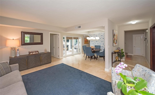 living room featuring french doors, a chandelier, and light tile patterned flooring