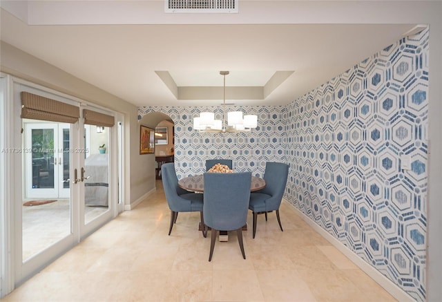 dining area featuring french doors, a raised ceiling, and a chandelier