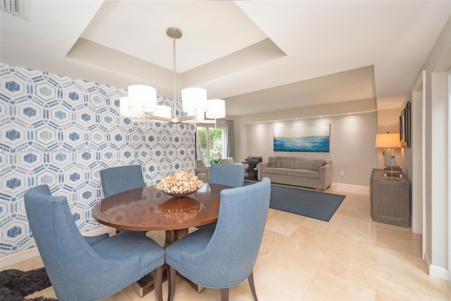 dining space with a chandelier and a raised ceiling