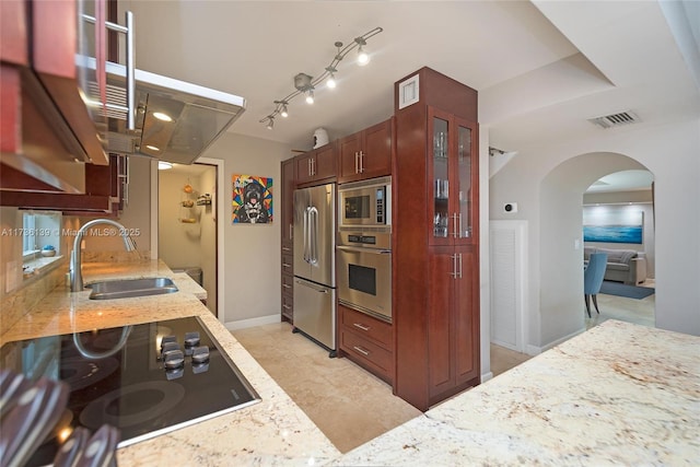 kitchen with sink, track lighting, light stone countertops, and appliances with stainless steel finishes