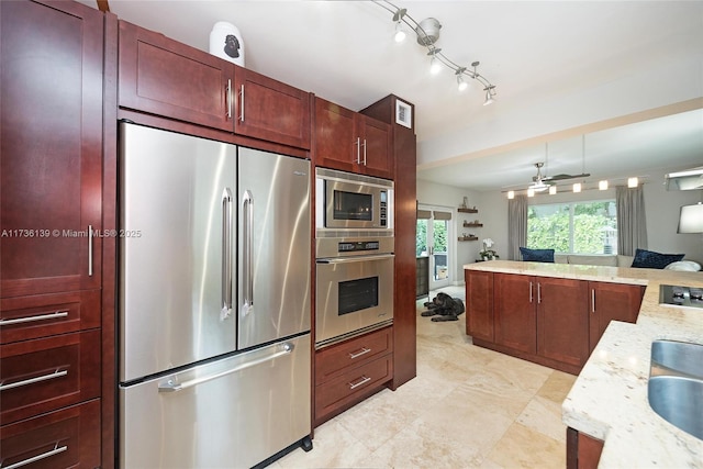 kitchen with light stone countertops, appliances with stainless steel finishes, sink, and ceiling fan