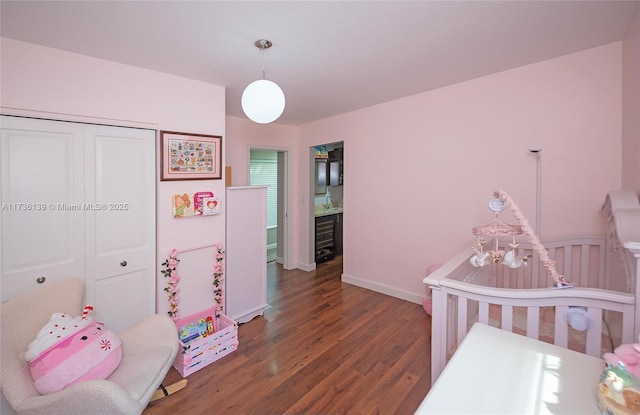 bedroom featuring dark wood-type flooring, a closet, and a crib