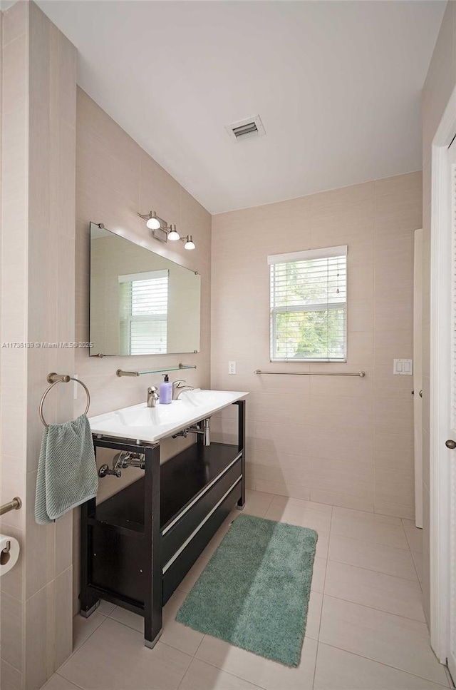 bathroom with a healthy amount of sunlight, vanity, tile patterned flooring, and tile walls