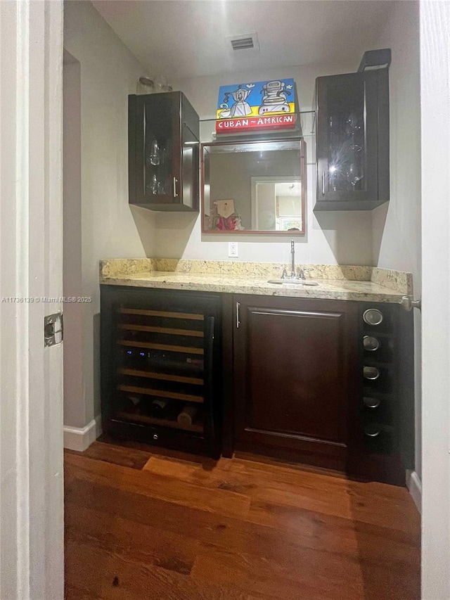 bar featuring light stone countertops, sink, and dark hardwood / wood-style flooring