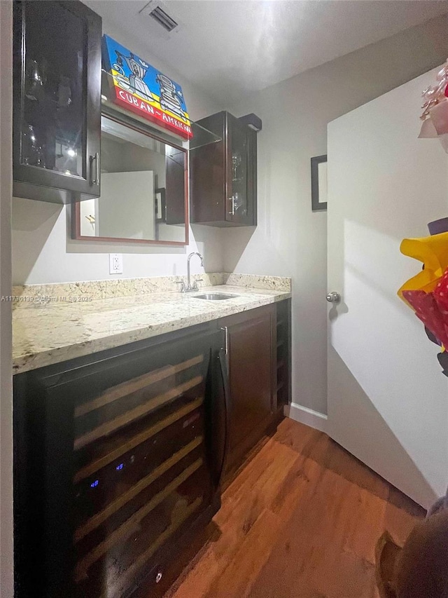 kitchen with light stone countertops, dark brown cabinets, sink, and dark hardwood / wood-style floors