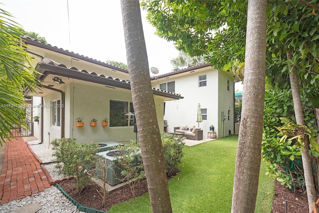 back of house with a patio, outdoor lounge area, a lawn, and central air condition unit