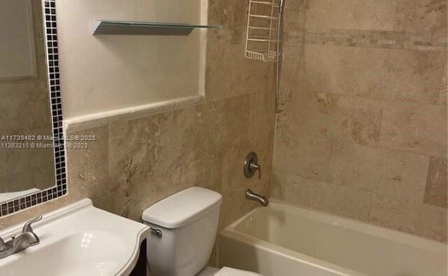 full bathroom featuring tile walls, sink, tiled shower / bath combo, and toilet