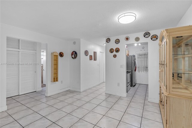 tiled empty room featuring a textured ceiling