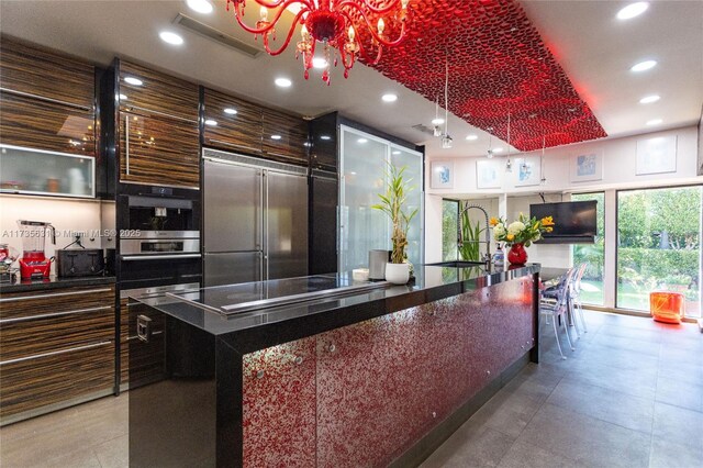 kitchen featuring sink, stainless steel appliances, floor to ceiling windows, a kitchen island, and decorative light fixtures