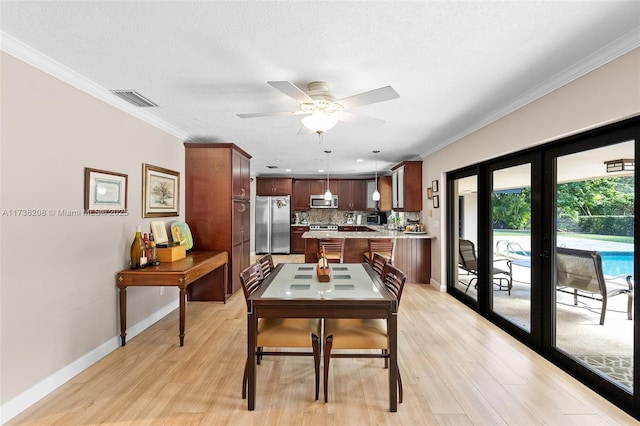 dining area featuring ceiling fan, ornamental molding, light hardwood / wood-style floors, and a textured ceiling