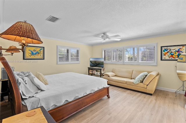 bedroom with multiple windows, crown molding, a textured ceiling, and light hardwood / wood-style flooring