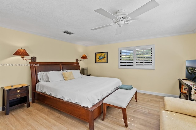 bedroom featuring ceiling fan, ornamental molding, a textured ceiling, and light wood-type flooring