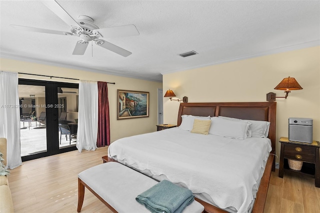 bedroom featuring light hardwood / wood-style flooring, access to exterior, a textured ceiling, and french doors