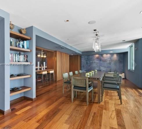 dining space featuring hardwood / wood-style flooring and a chandelier