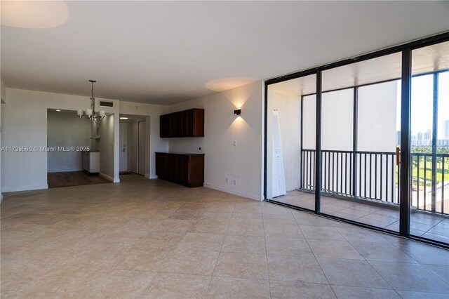 unfurnished living room with light tile patterned flooring, a wall of windows, and a notable chandelier