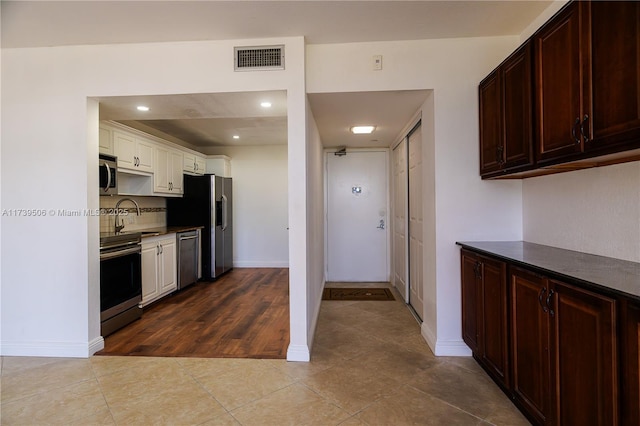 kitchen with appliances with stainless steel finishes, sink, decorative backsplash, and light tile patterned floors