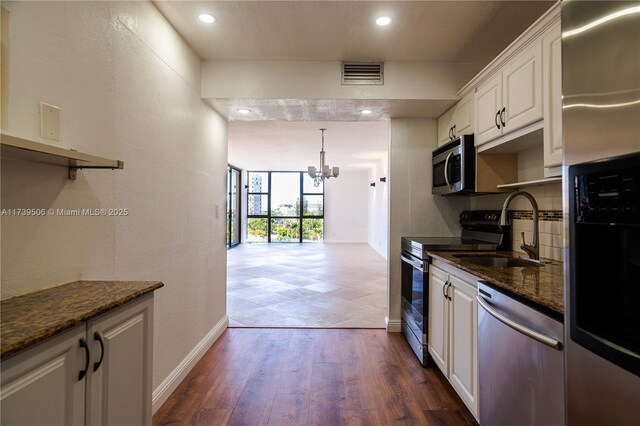 kitchen featuring sink, white cabinetry, dark stone countertops, stainless steel appliances, and dark hardwood / wood-style floors