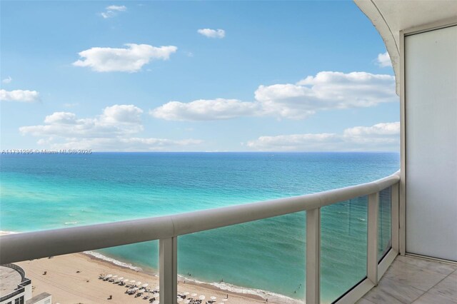 balcony with a water view and a view of the beach