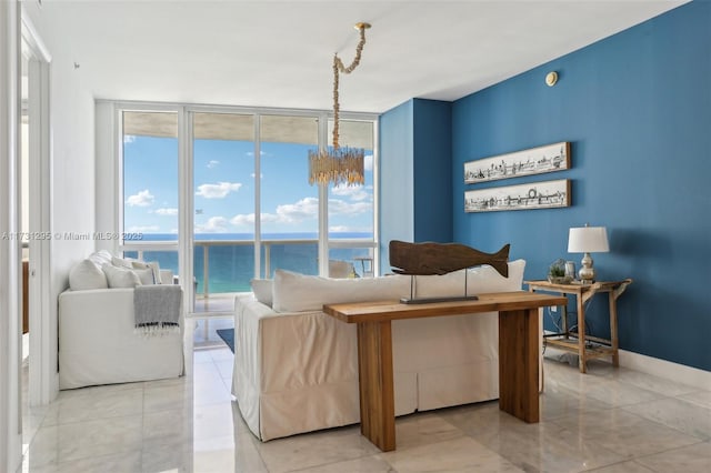 living room featuring baseboards, a water view, an inviting chandelier, and floor to ceiling windows