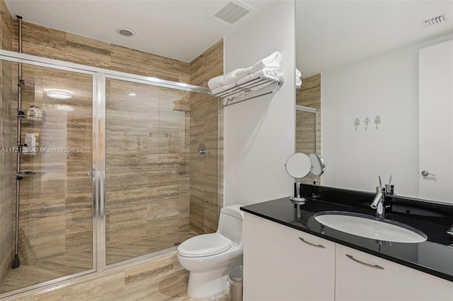 bathroom featuring toilet, a stall shower, vanity, and visible vents