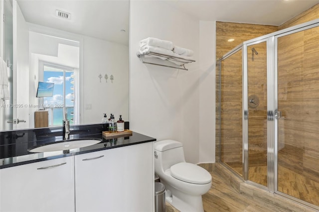 full bath with visible vents, toilet, vanity, a shower stall, and wood finished floors