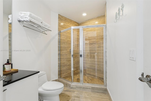 bathroom featuring toilet, a shower stall, and vanity